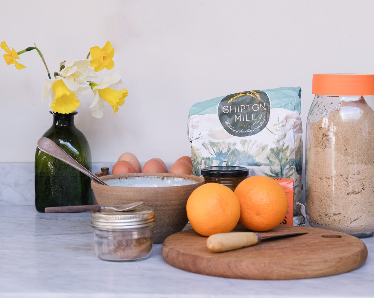 a kitchen worktop with all the ingredients needed to make Easter hot cross buns