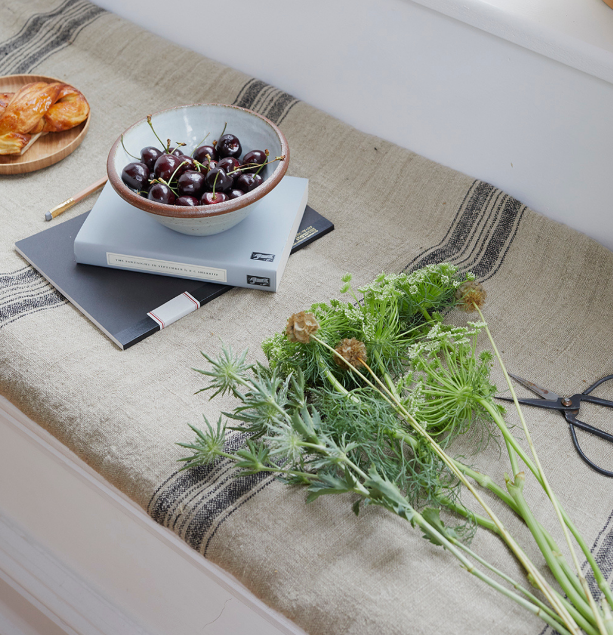 a window seat with a bunch of flowers and a feel good book