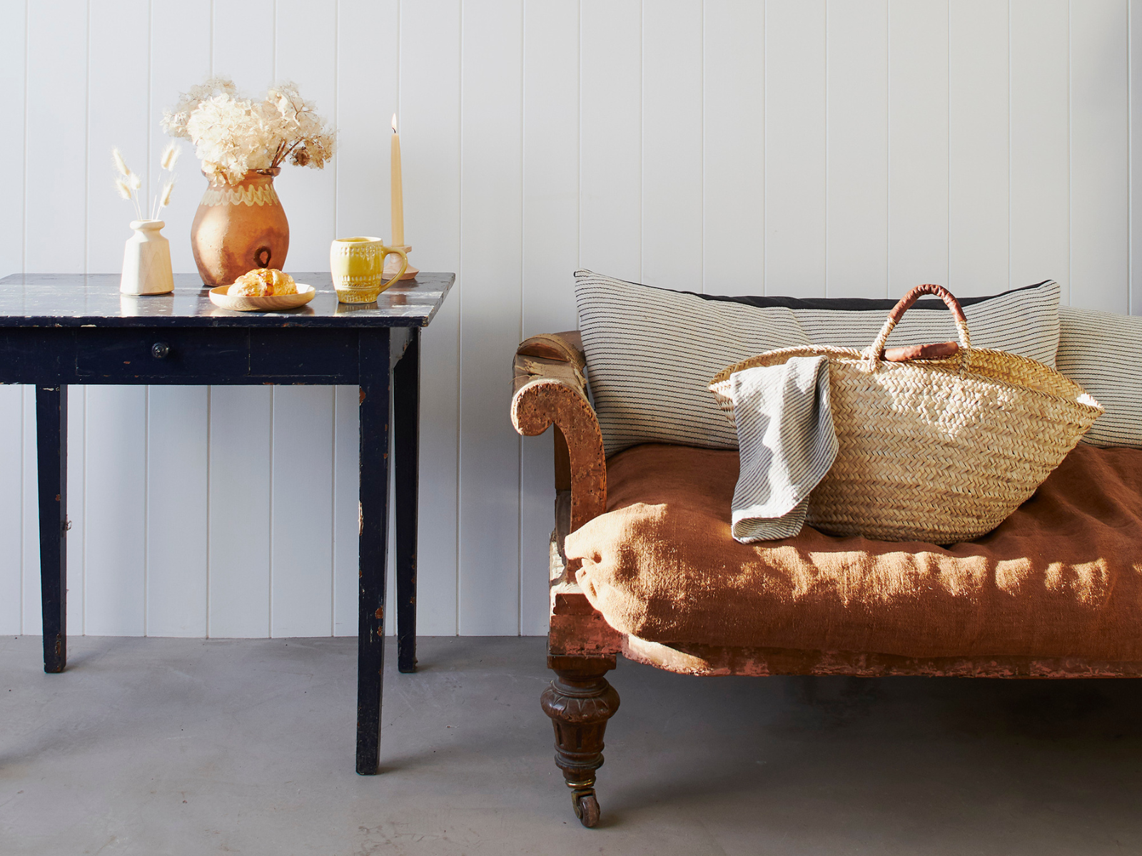 a rustic sofa with cushions and a side table with candles and flowers