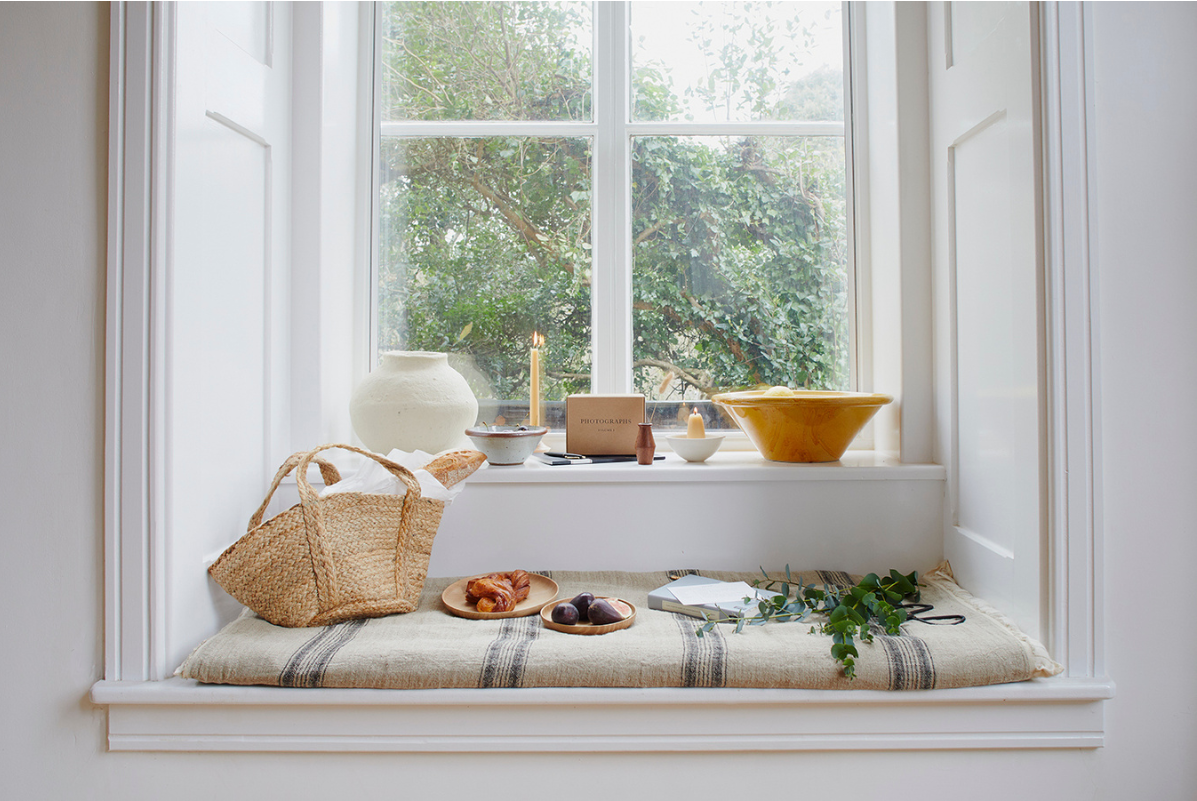 A basket, bowls and a blanket on a window sill