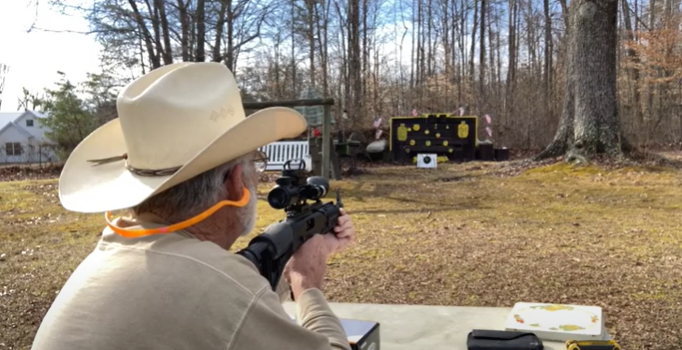A man is adjusting his rifle scope to properly sight it in to accurately hit targets | Pinty Scopes