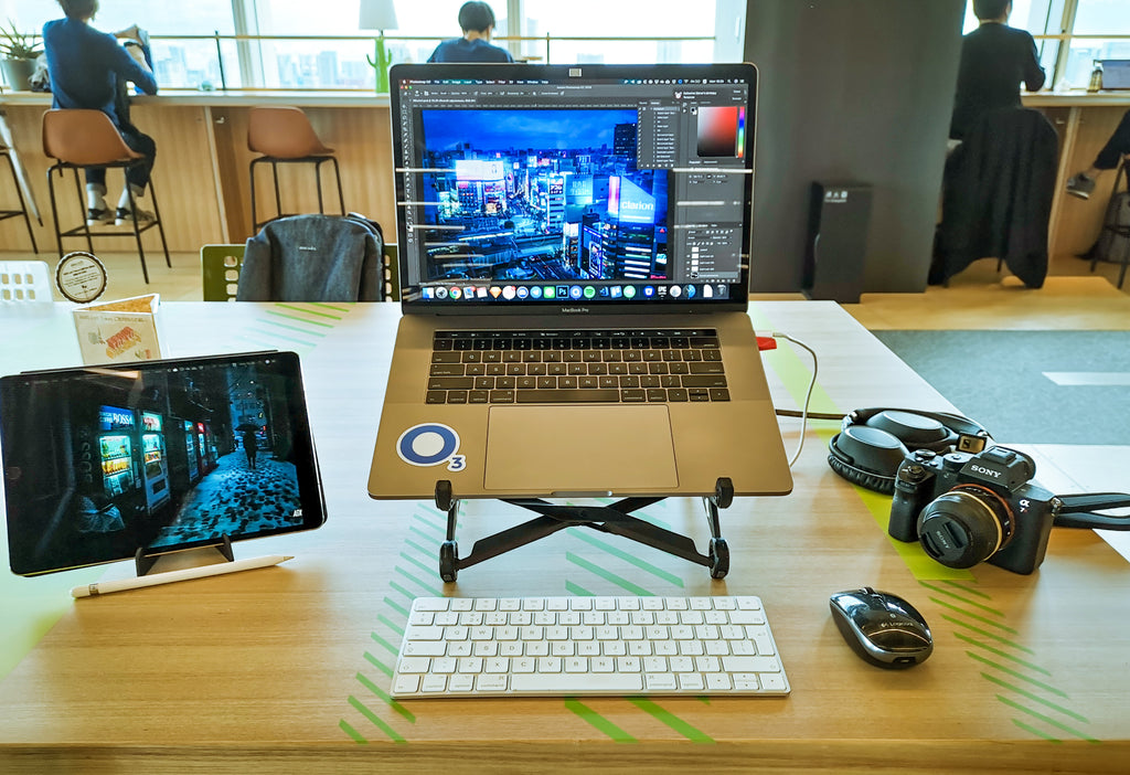 A workstation in a cafe featuring a laptop, tablet, and wireless accessories. 