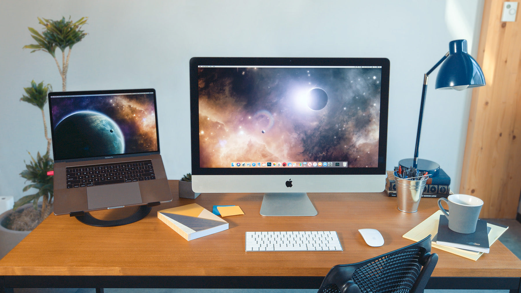 A workstation with a laptop, apple monitor, and wireless keyboard and mouse. 