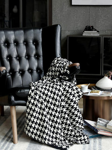 Classic Houndstooth Blanket in Black and White draped over a black, leather reading chair