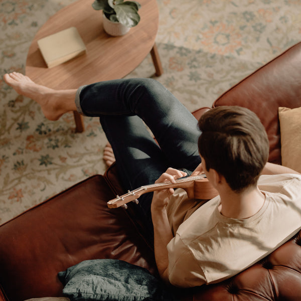 Junger Mann spielt Ukulele auf der Couch