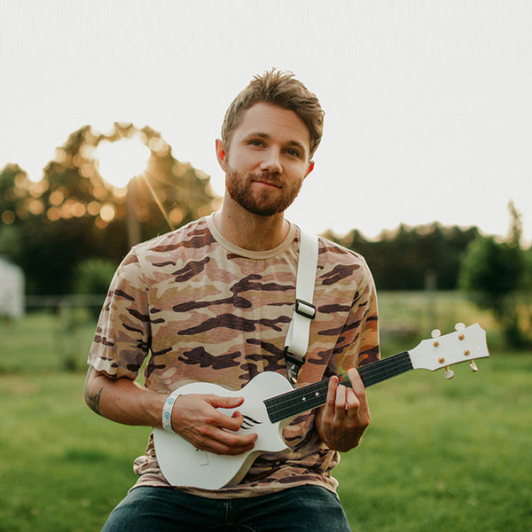 Junger Mann auf Festival spielt eine weiße Travel Ukulele  