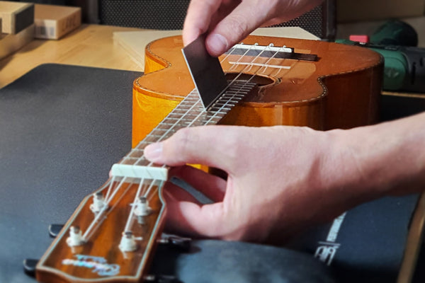 Nahaufnahme einer Ukulele beim Check der Saitenlage 