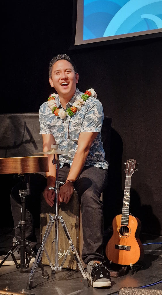 Abe Lagrimas, Jr. mit Cajon, Rassel und Ukulele auf der Bühne