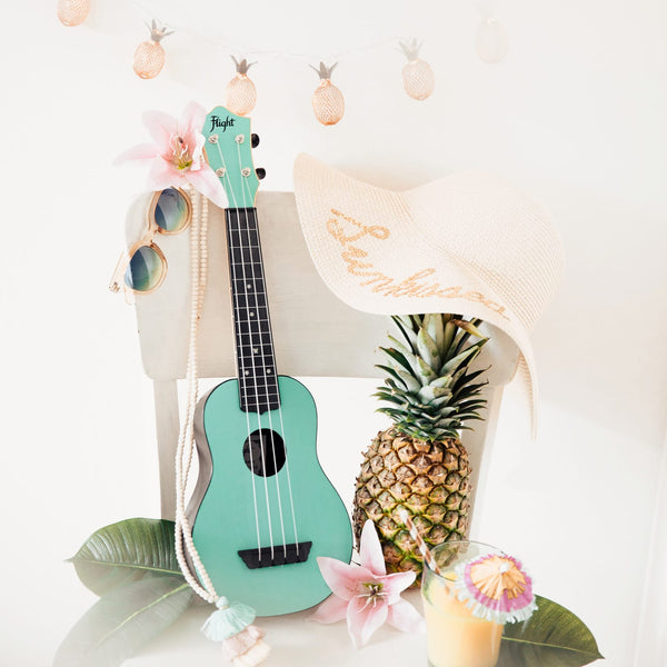 Türkisfarbene Travel Ukulele von Flight mit Ananas, Sonnenhut und sommerlicher Deko