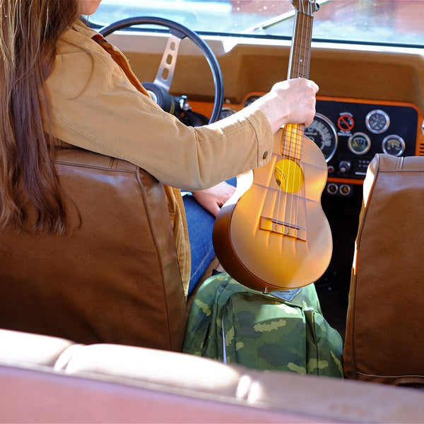 Frau auf Ledersitzen im Auto mit Kunststoff-Ukulele