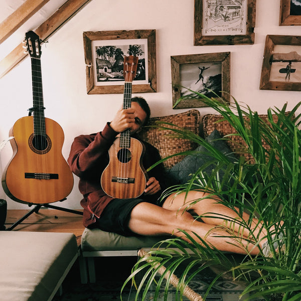 Mann liegt auf dem Sofa neben einer Gitarre und Ukulele