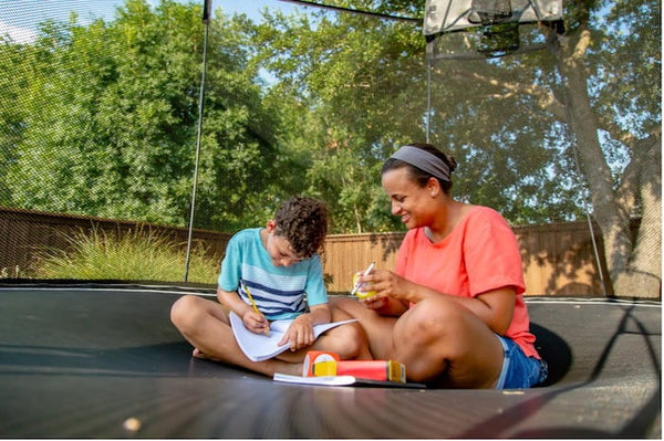 A mother and her son doing homework on a trampoline.