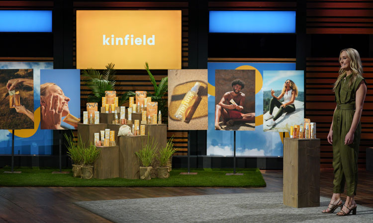 Nichole Powell of Kinfield stands on the set of ABC Shark Tank with her display of Kinfield products in the background.