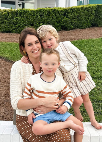 Pepa sitting outside on a low wall with Hudson in her lap and Matthew leaning beside her.