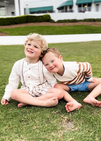Matthew and Hudson sitting next to each other outside on a green lawn.