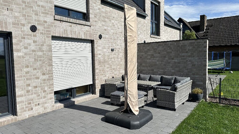 A modern patio with a covered umbrella, wicker furniture, and a stone wall.