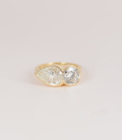 Bellamy's Two Stone Track Ring. Her larger pear shaped diamond and round diamond are in a track setting on a delicate half round band.