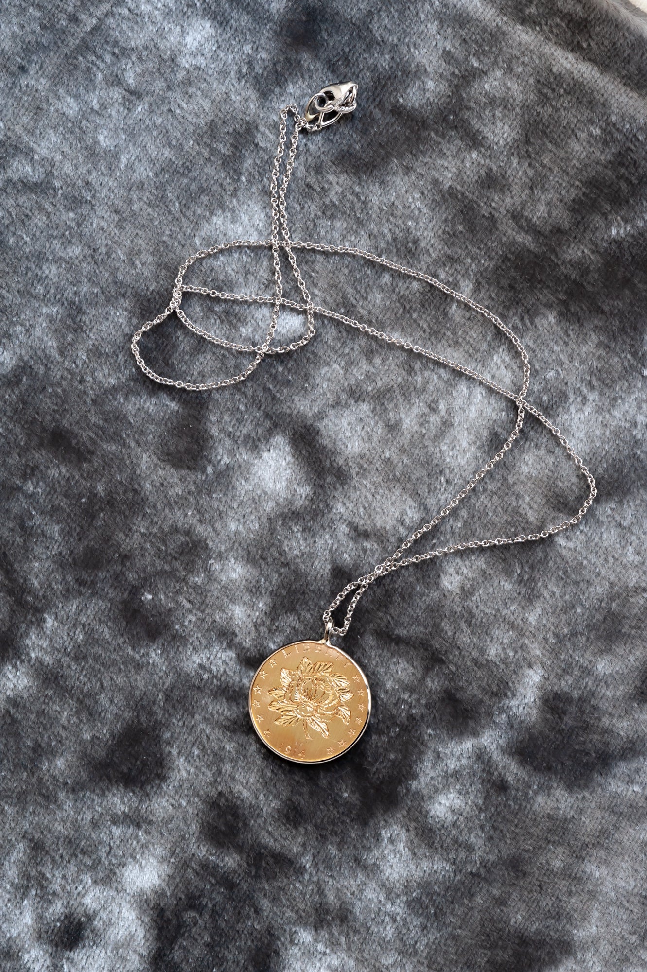 A hand engraved mangolia on a gold coin, set on a delicate cable chain in mixed metals.
