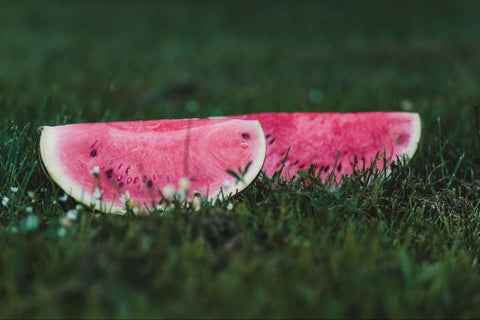 Two large slices of watermelon resting in the green grass.