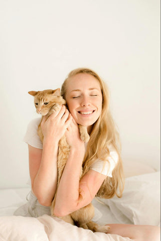 Woman cuddling with an orange tabby cat