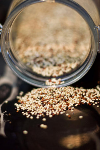 A jar of tricolor quinoa spilling some contents