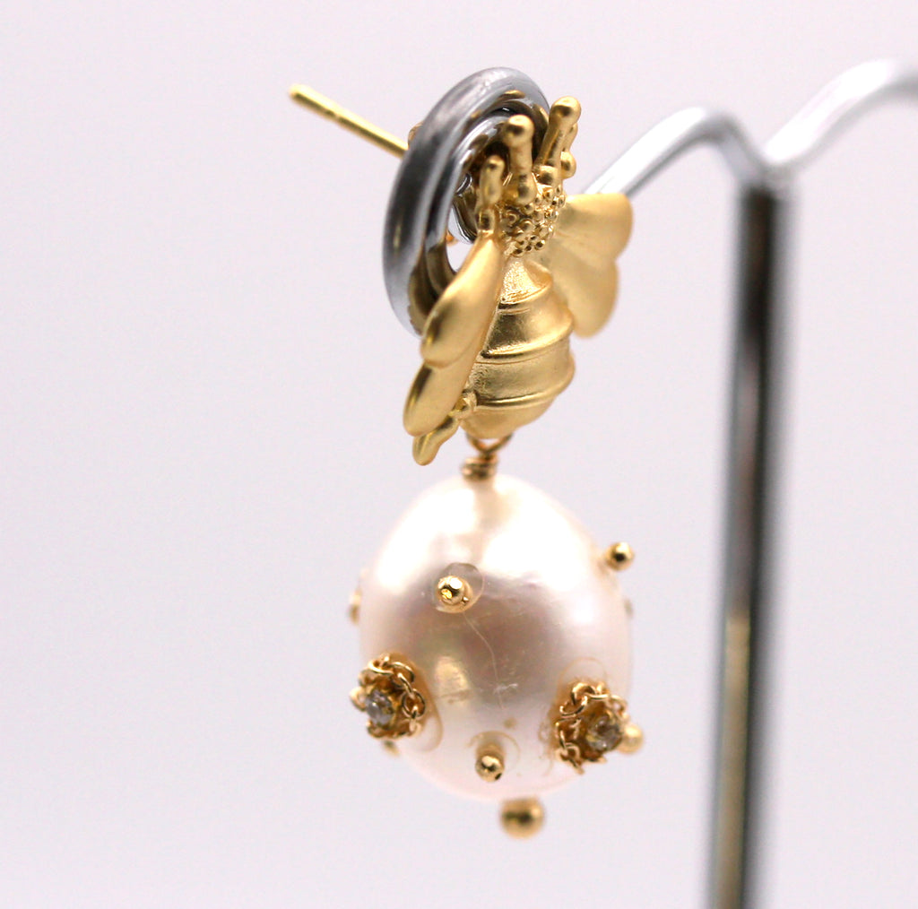 Genuine freshwater pearl earrings.  The 12 mm diameter white pearl is decorated with clear zircon gemstones. The pearl dangles below a gold plated sterling silver bumble bee post. Side view
