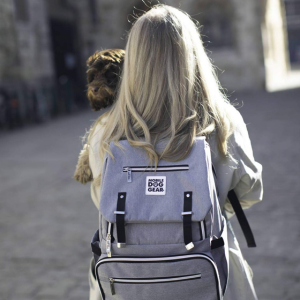 Blonde woman on a walk with their cockapoo wearing a grey mobile dog gear backpack