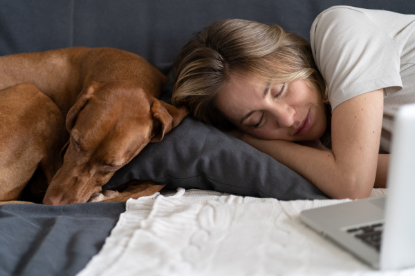 Woman and a brown dog sleeping together on a bed