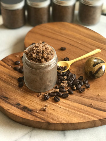 Coffee Scrub in a frosted glass jar with a wooden spoon