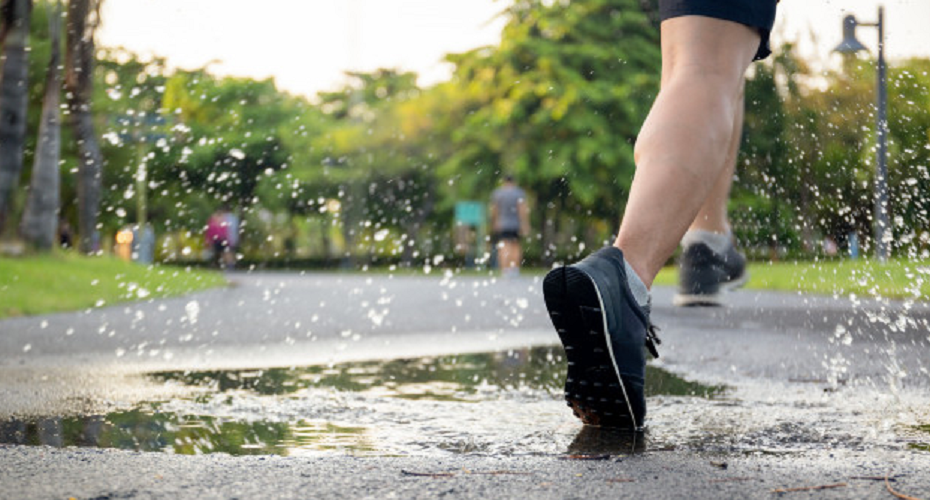 Man runs through the puddles splashing his shoes.