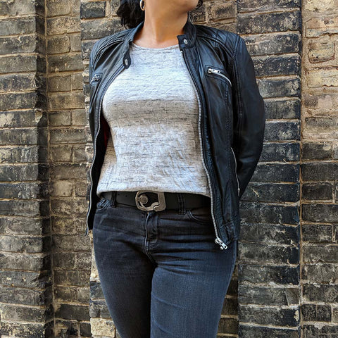 skeleton belt on wife wearing jeans, leather jacket, pair of silver earrings, and a non traditional watch