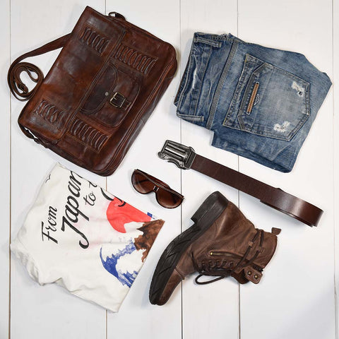 Men's fashion flat lay. Style a brown gun belt, blue jeans, and pair of cowboy boots to create a western look.