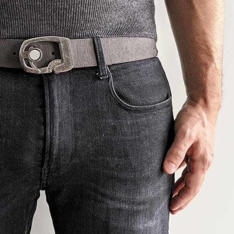 Dark Jeans with a Skeleton buckle on distressed grey leather. The extra strap is behind the loop.