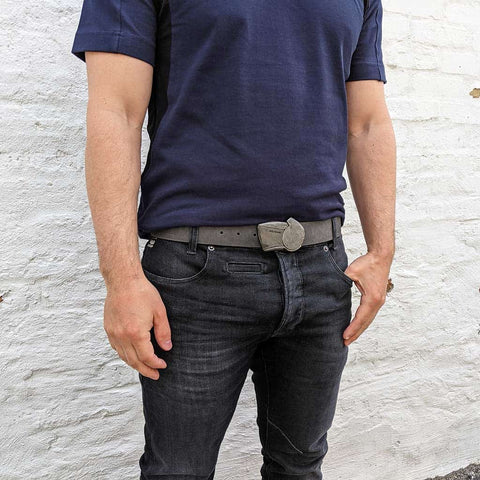 sundial belt on distressed leather worn with black jeans and a blue t-shirt in a grungy alley