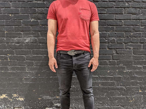 excalibur belt worn with black jeans and a red t-shirt in a grungy alley