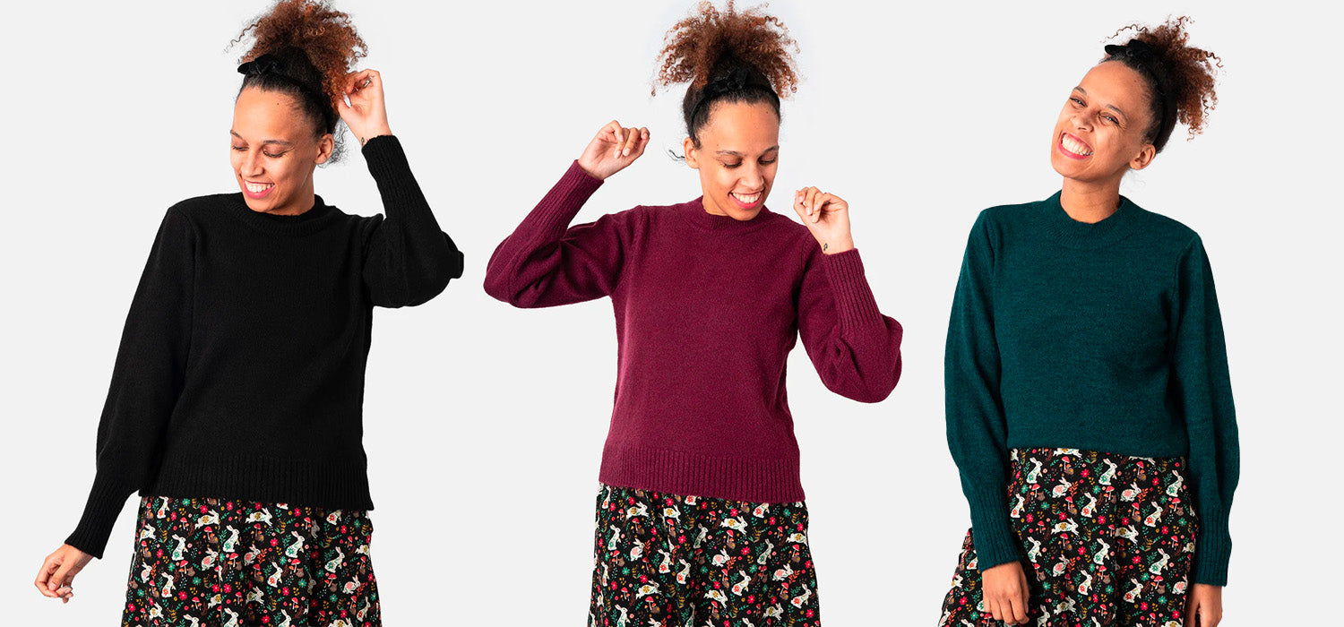 Three women wearing different coloured jumpers, black, burgundy and dark pine green on white background.