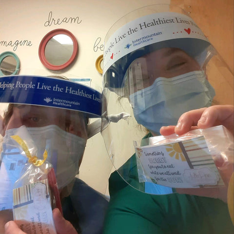 Two healthcare workers wearing PPE and holding treats from JulieAnn Caramels.