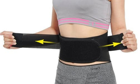 Femme UTILISEla ceinture de soutien lombaire magnétique et chauffante qui la serre autour de la taille avec les élastiques. oubliez-la-douleurs