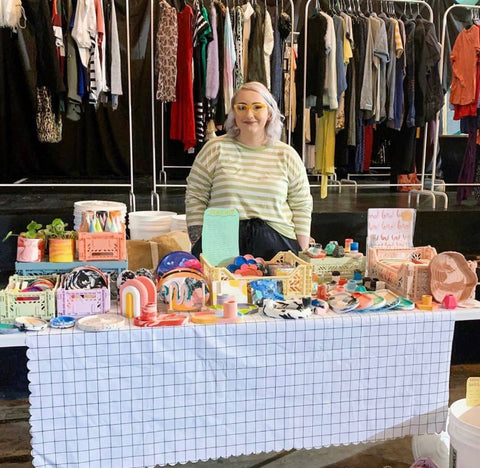 Jodie stands at her table at a vendor market with terrazzo pieces 