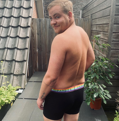 Tijn in Paxsies underwear, back facing the camera as they look toward the camera