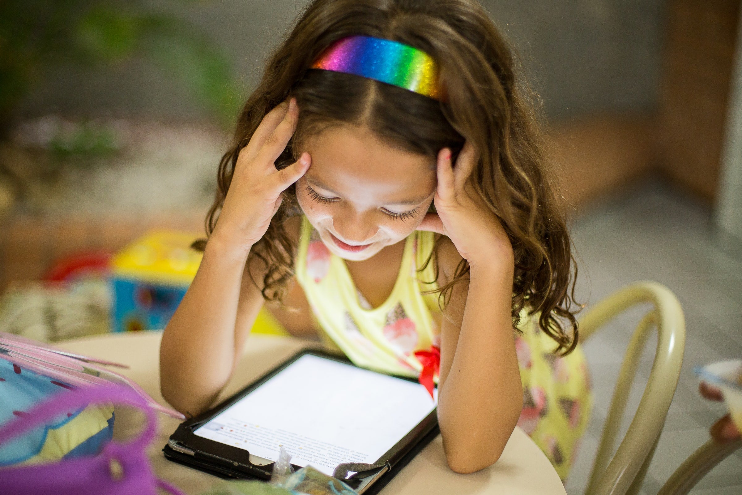 little girl with rainbow headband watching tv on a tablet. image by Patricia Prudente on unsplash