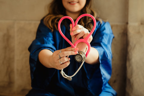 woman in scrubs holding up stethoscope in heart shape, image by Patty Brito on unsplash