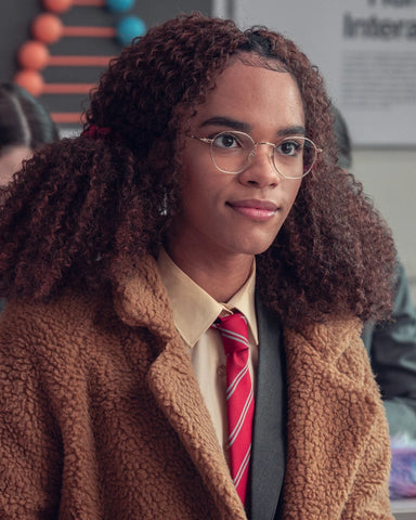 Photo of Elle. She weras glasses, a light brown coat and her school uniform underneath.