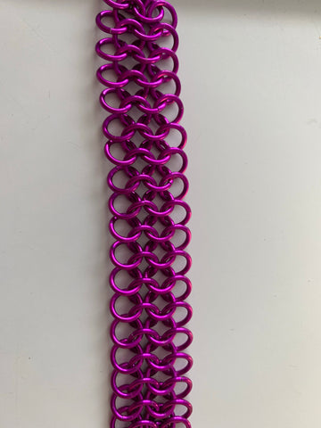 A strip of violet colored chainmaille fabric