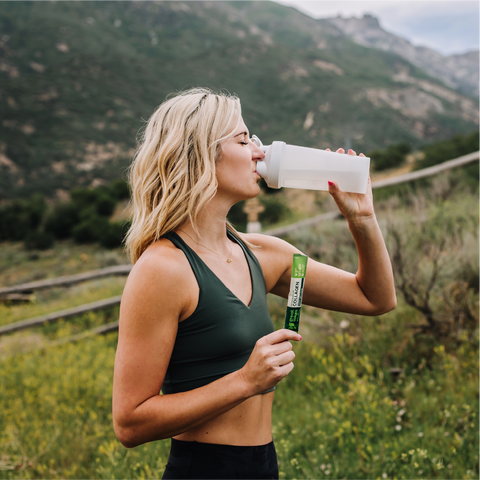 young fit girl drinking collagen in mountains on a hike