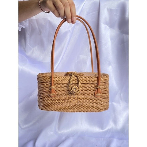 Rattan bag paired with a summer dress on a beach.