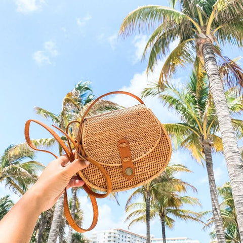 Stylish rattan backpack on a wooden background.