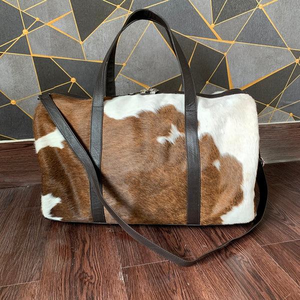 This stylish cowhide duffle purse is perfect for any event or trip - it's easy to carry and features a spacious main compartment, plus an interior pocket for extra organization.