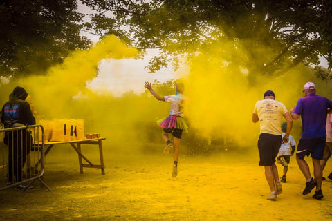 Man jumping through yellow colour powder