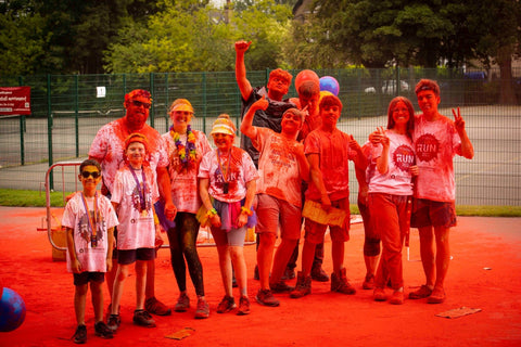 Group of people at colour run event, covered in red colour powder